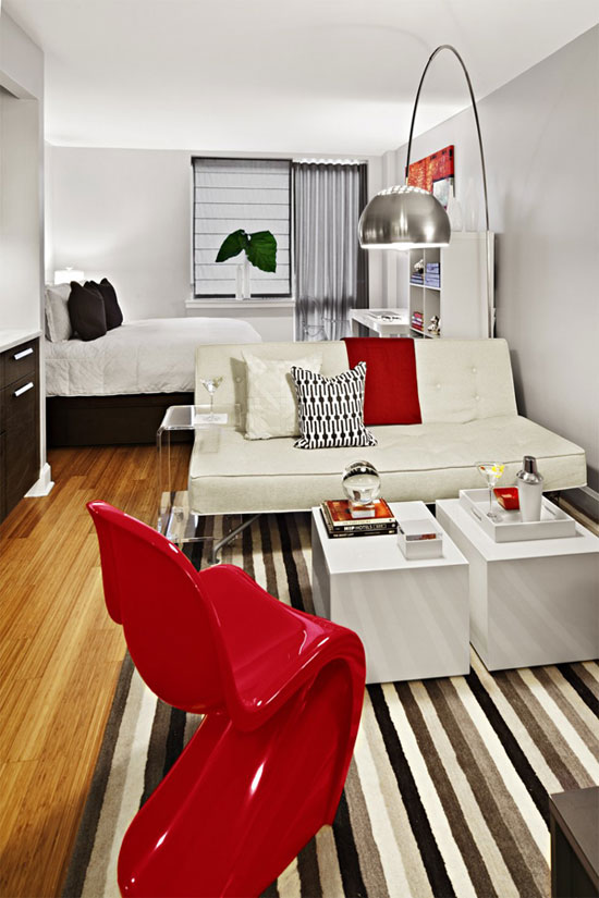 Mẫu căn hộ này được phân chia không gian giữa bàn tiếp khách và giường ngủ bằng rèm màu ghi rất khéo léo. Như với các căn hộ nhỏ khác, căn hộ này cũng được sử dụng tường trắng và đồ nội thất màu sáng để tạo cảm giác rộng rãi và thoáng mát về mặt thị giác. Điểm nhấn của căn hộ là chiếc ghế màu đỏ phối cùng với những đồ decor nhỏ khác tạo nên một không gian hoàn hảo cho căn hộ.